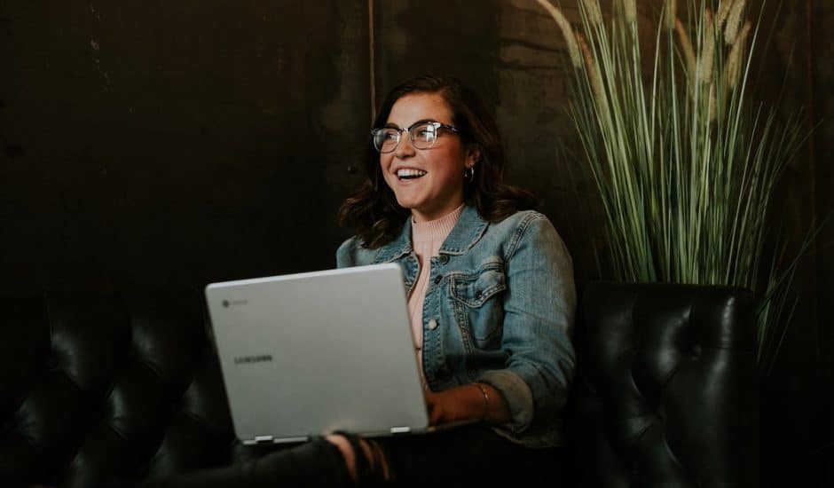 une femme souriante devant son ordinateur portable