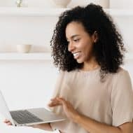une femme souriante tenant un ordinateur portable gris dans ses mains