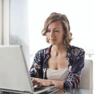 une femme à son bureau devant un ordinateur portable gris