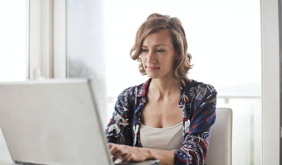 une femme à son bureau devant un ordinateur portable gris