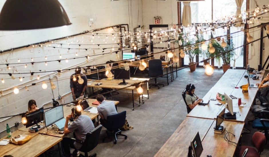 un espace de coworking avec des personnes qui travaillent sur des bureaux et des guirlandes lumineuses au plafond