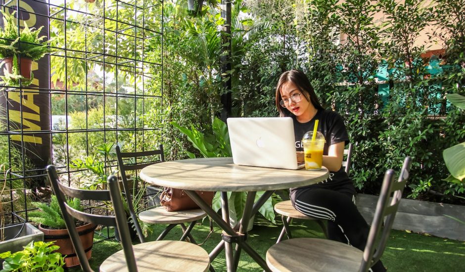 une femme devant son ordinateur sur une table, entourée de plantes