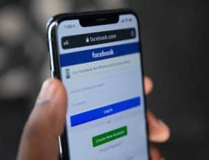 Une personne tenant son smartphone avec l'écran de connexion de Facebook, le réseau social de Meta