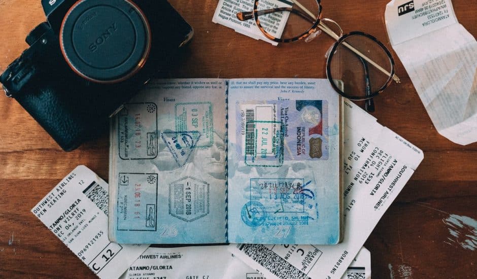 un passeport ouvert et tamponné sunr une table en bois avec un appareil photo et des lunettes