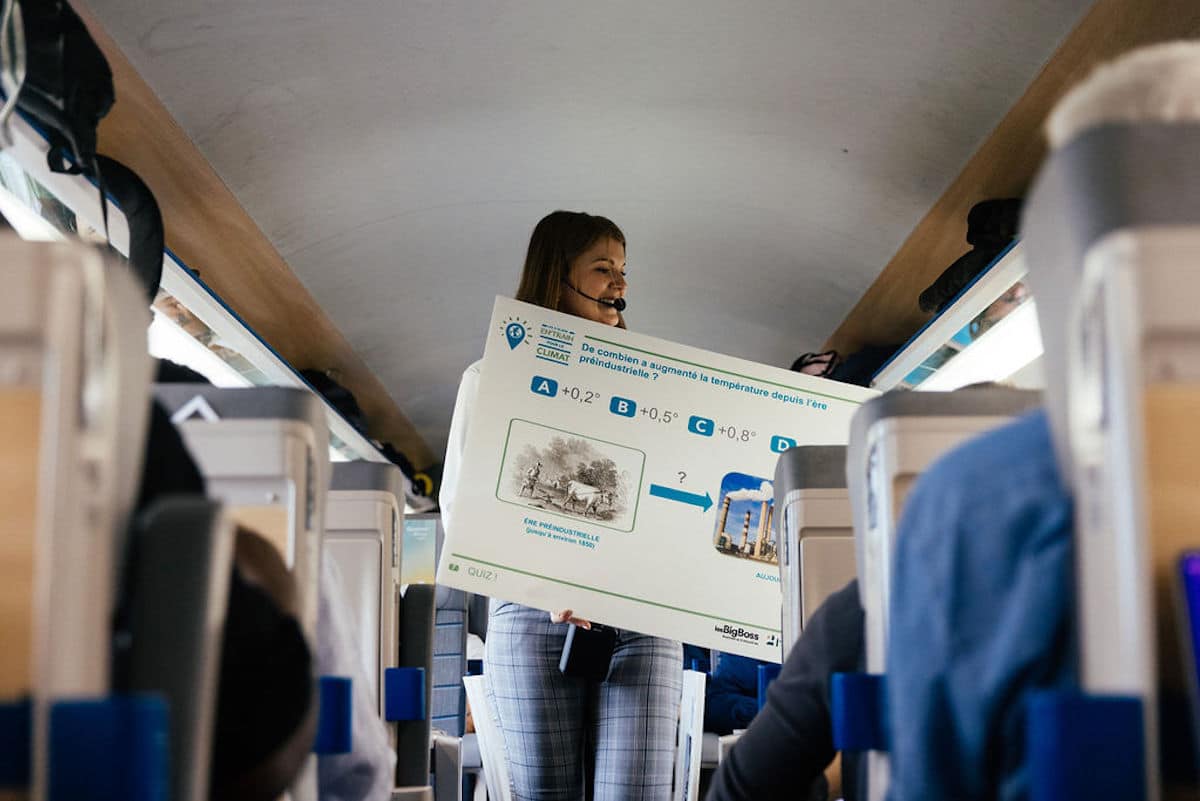 une femme avec un panneau pour sensibiliser aux causes environnementales dans un train