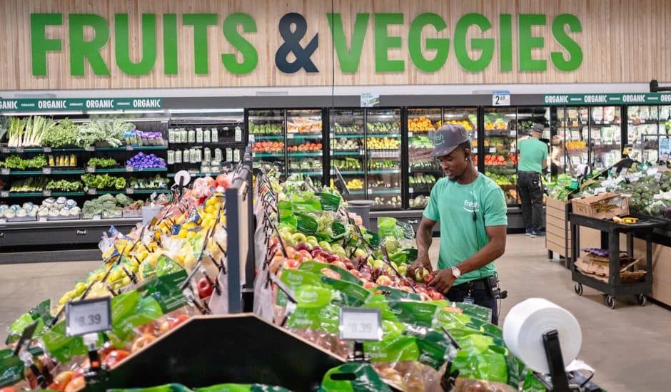 un employé amazon fresh devant un stand de fruits et légumes