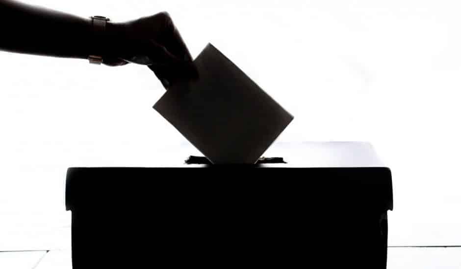 Une personne déposant un bulletin de vote dans une urne.