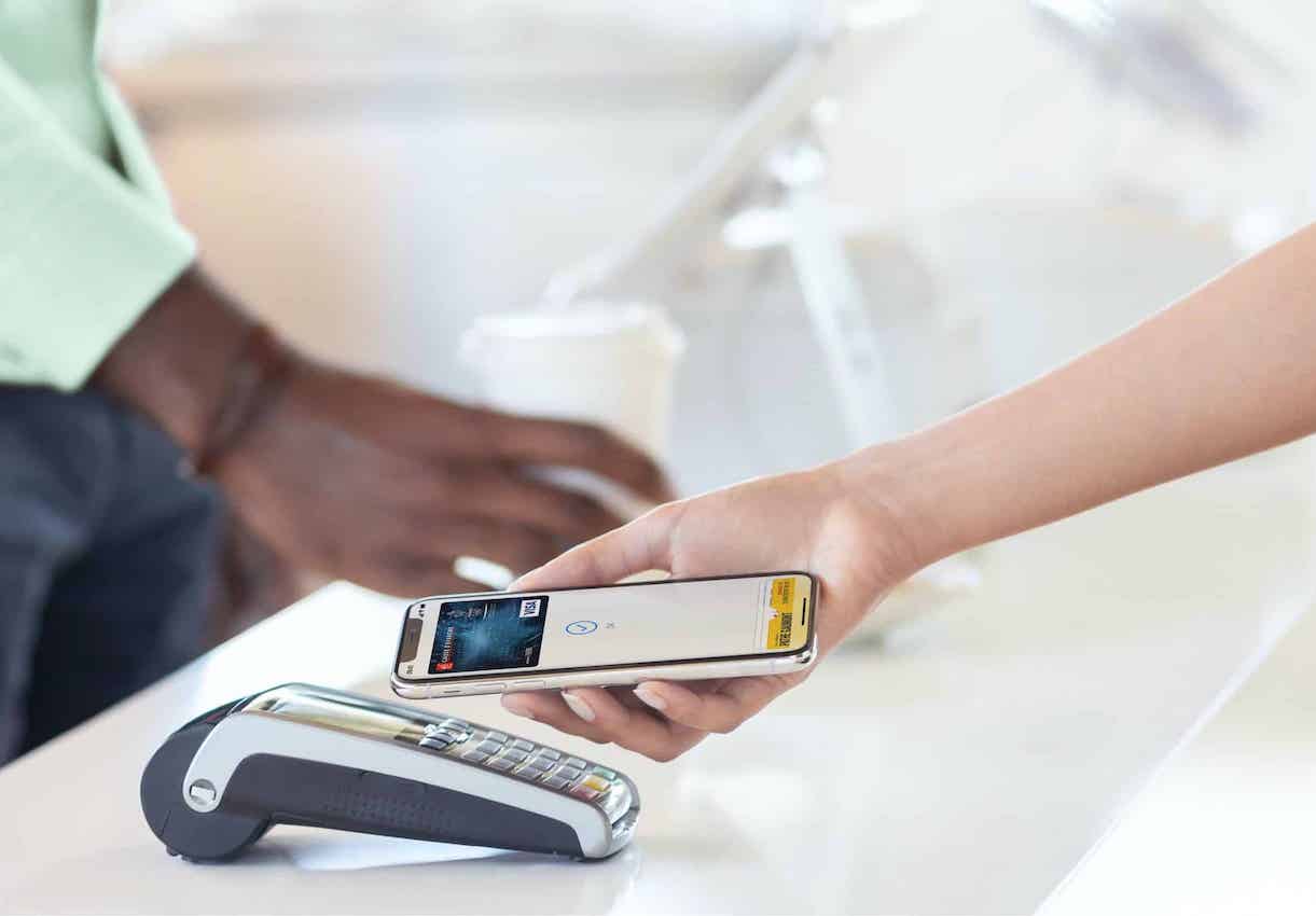 Le bras d'une personne tenant son smartphone afin d'effectuer un règlement avec Apple Pay.