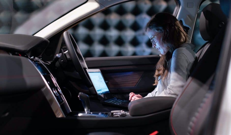 Une femme travaillant sur son ordinateur à bord d'une voiture.