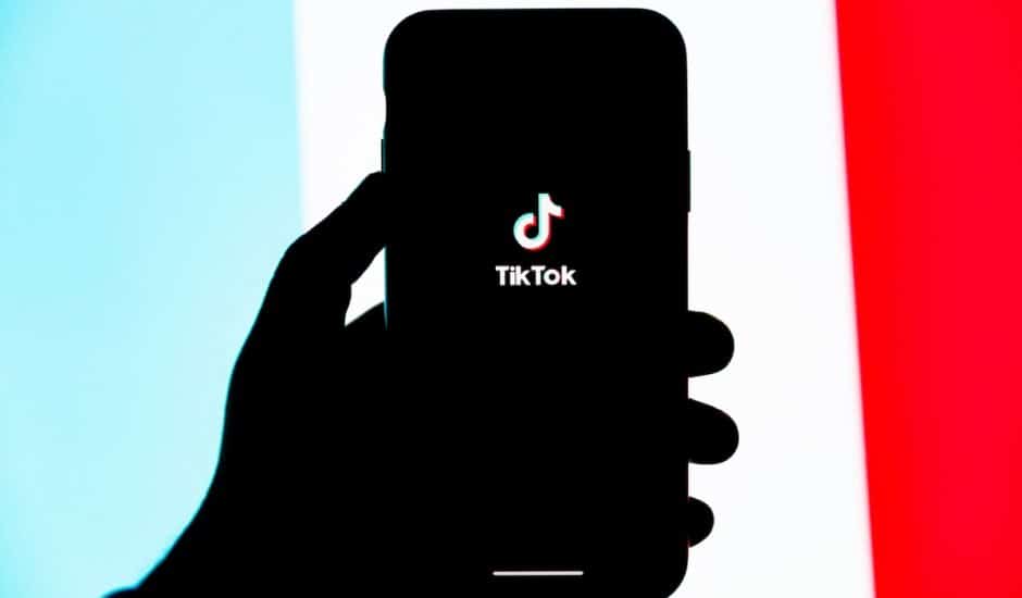 une personne tenant un smartphone avec le logo tiktok