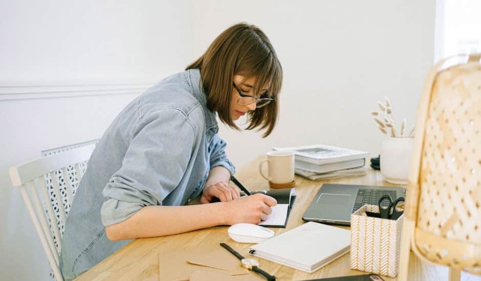 une femme à son bureau en train d'écrire dans un carnet