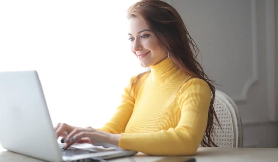 une femme souriante devant son ordinateur portable