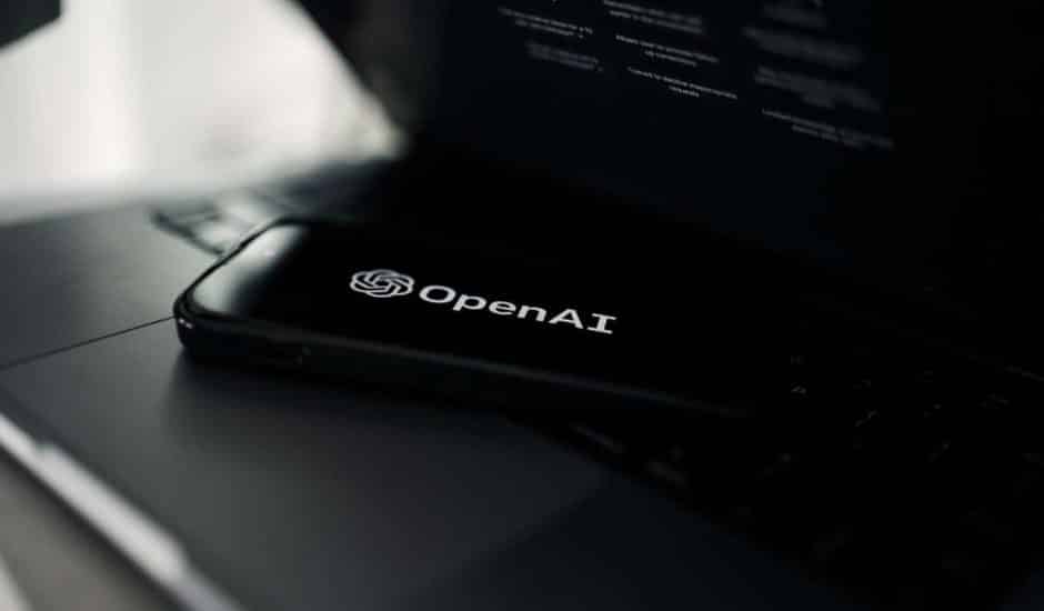 Logo d'OpenAI, à l'origine de GPT-4, sur un smartphone posé sur un clavier d'ordinateur portable.