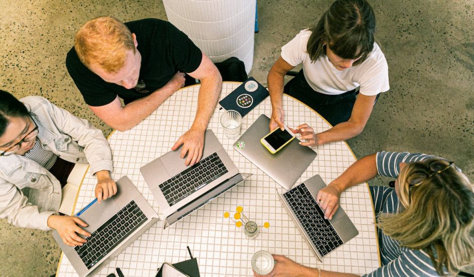 une équipe en réunion, des ordinateurs et smartphones sur la table devant eux