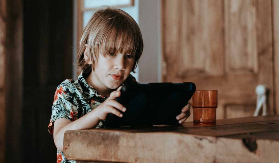 Un enfant regarde une tablette tactile.