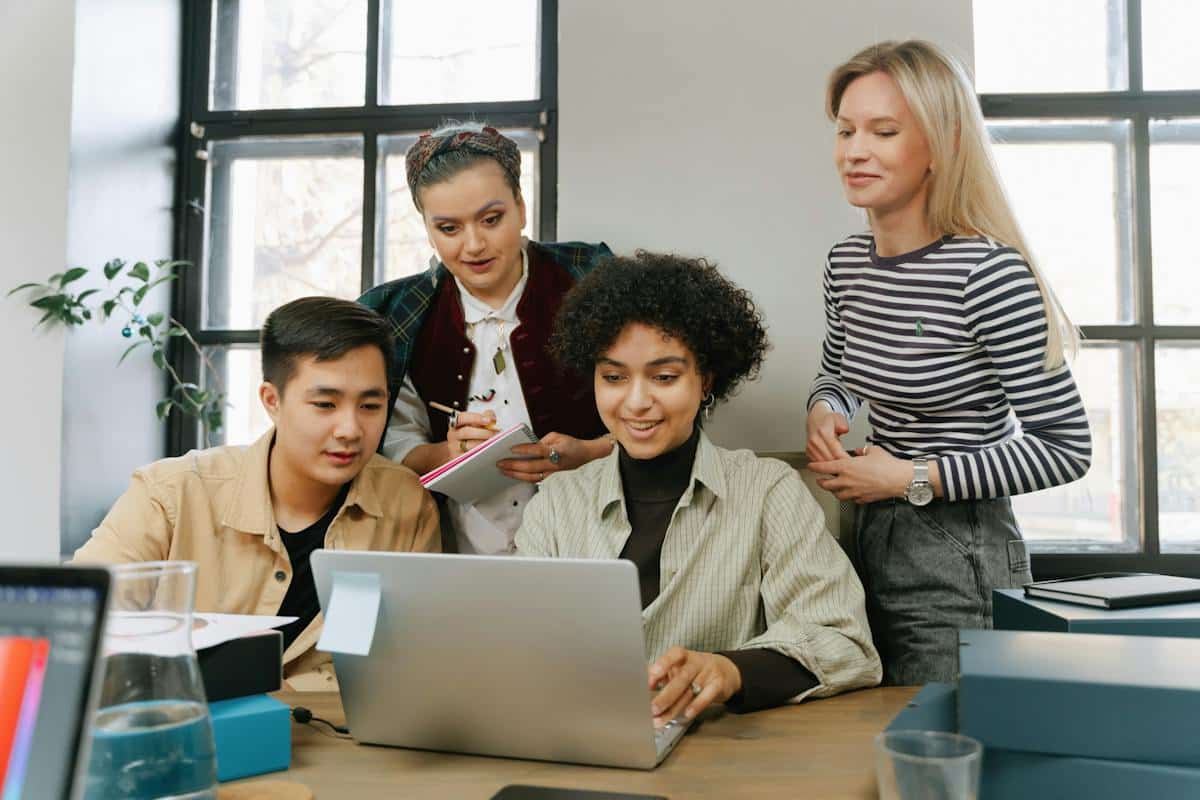 un groupe de quatre personnes au travail devant un ordinateur