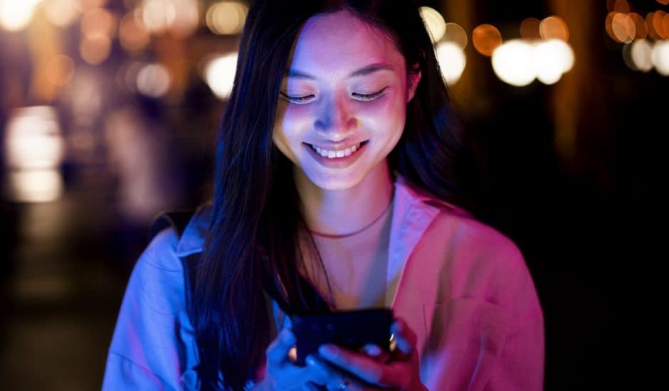 une femme souriante devant son smartphone