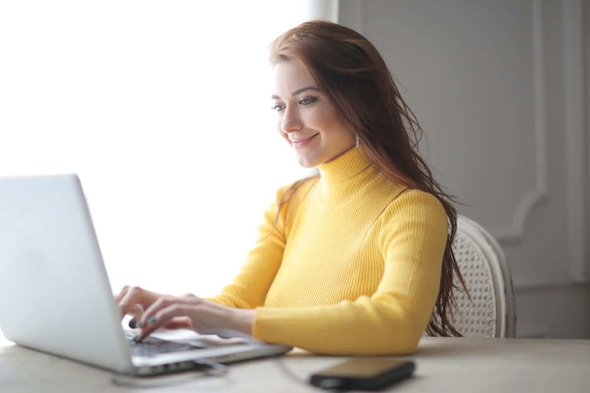une femme souriante devant son ordinateur