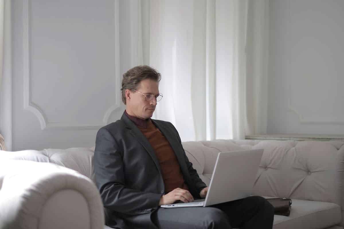 un homme assis sur un canapé avec un ordinateur sur ses genoux