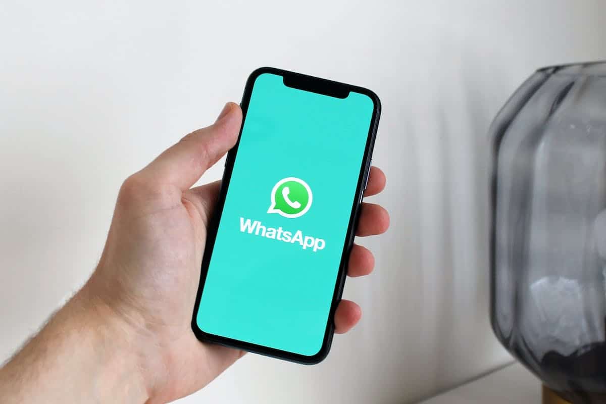 une personne tenant une smartphone avec le logo whatsapp affiché dessus