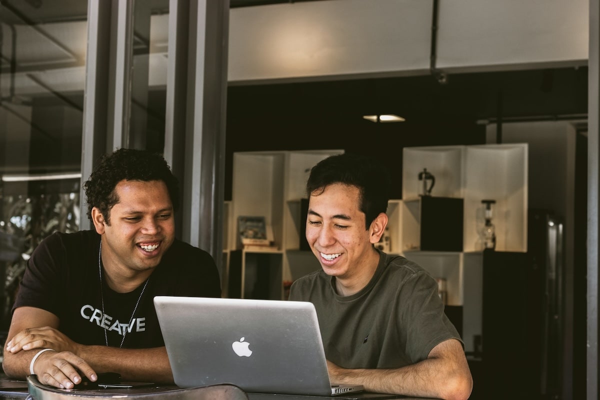 deux hommes souriant devant un ordinateur
