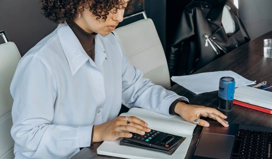 une femme en train d'utiliser une calculatrice à son bureau et de faire une facture électronique