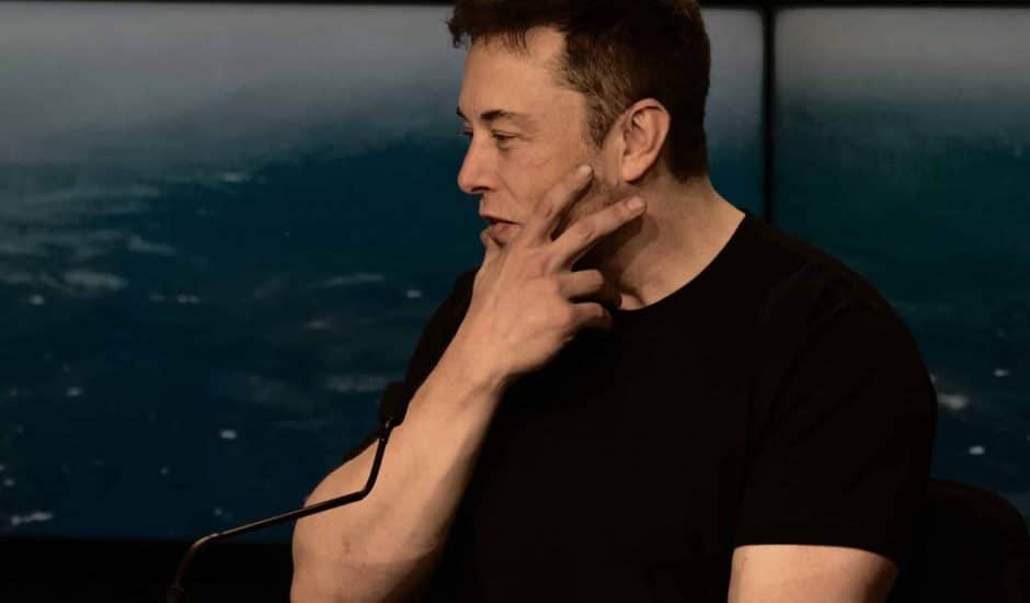 Elon Musk portant un t-shirt noir et se tenant le menton