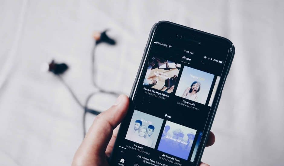 L'application Spotify sur un téléphone mobile avec des écouteurs en arrière-plan.